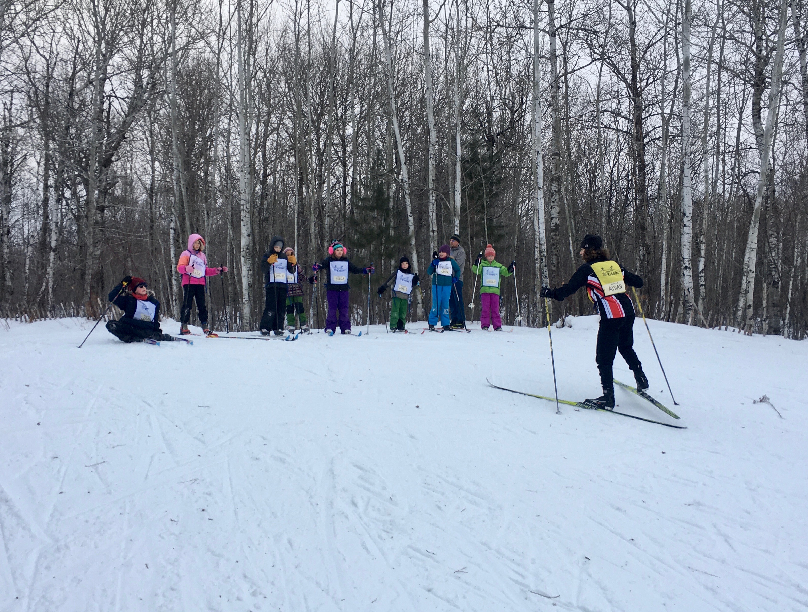 Kidski skiers lined up at the top of the hill